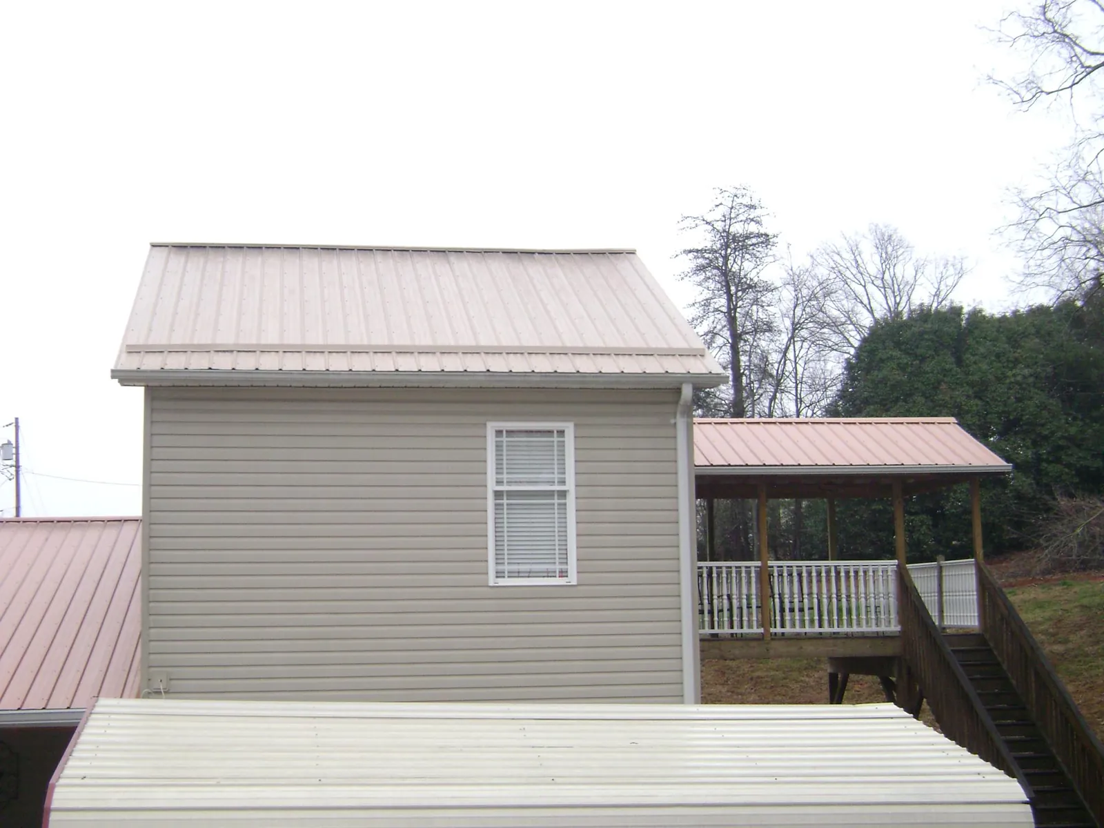 Tan metal roofs on a two story addition and attached porch, from a Roof Replacement job in Culpeper