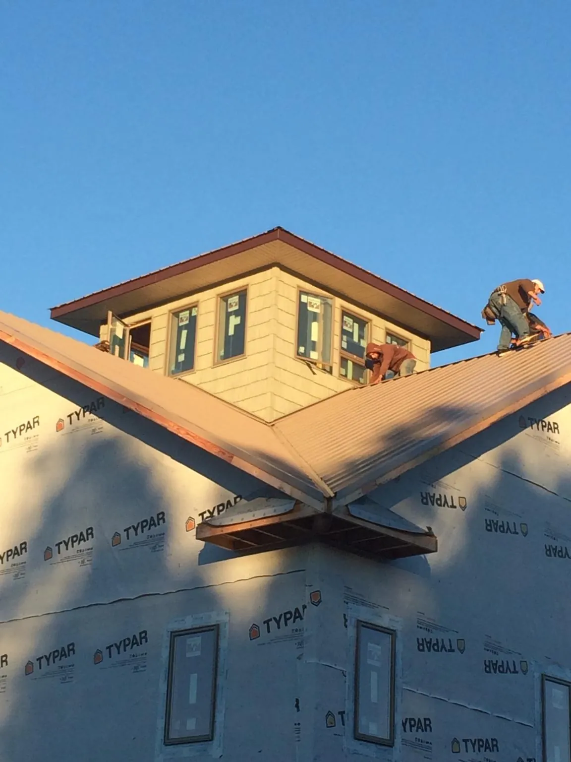 Roofers working around a rooftop cupola on a new metal roof at sunset — Roof Waterproofing in Culpeper by Roofing Brothers